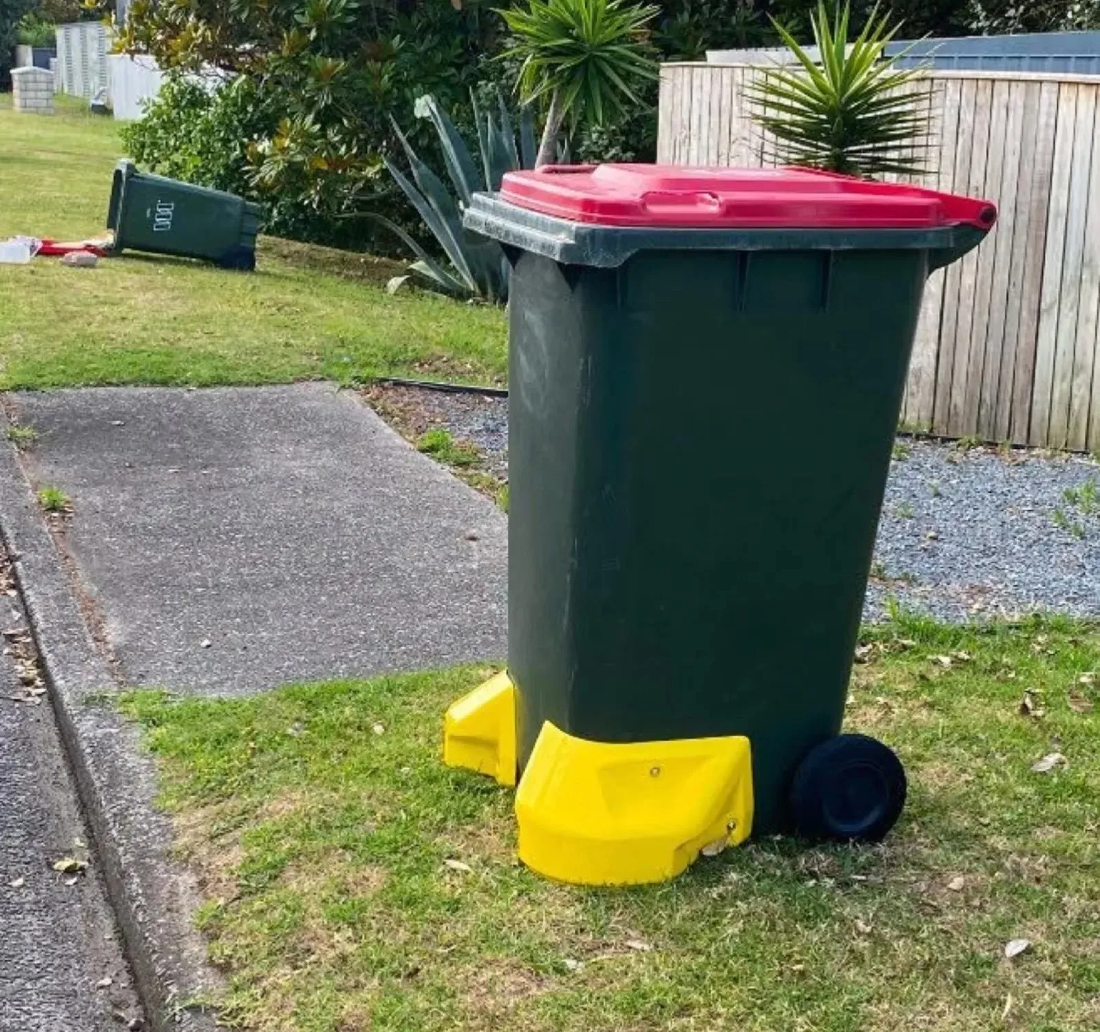 A stable wheelie bin with BinUpright beside another bin that has tipped over